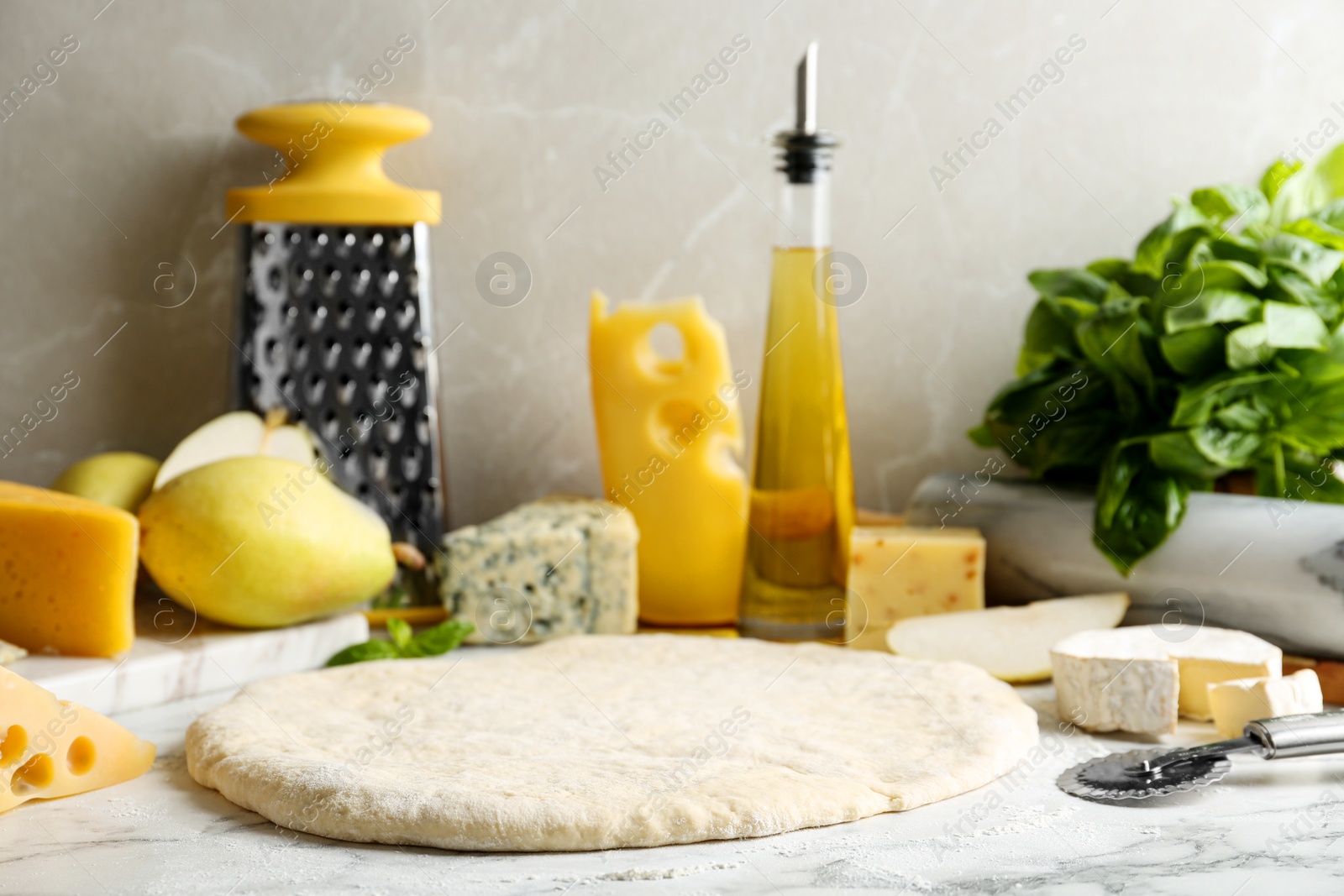 Photo of Pizza crust and fresh ingredients on marble table