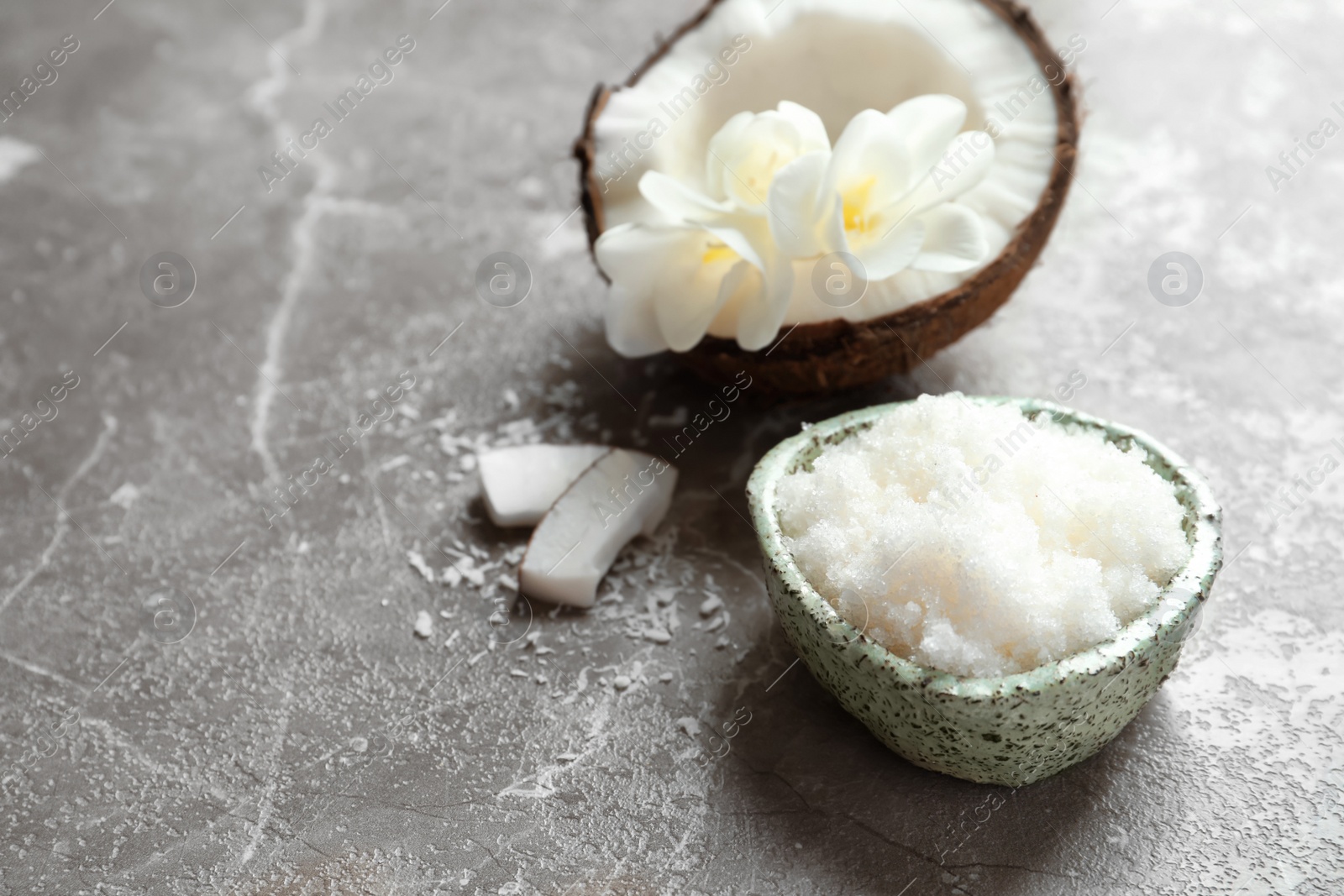 Photo of Bowl with natural coconut scrub on grey background