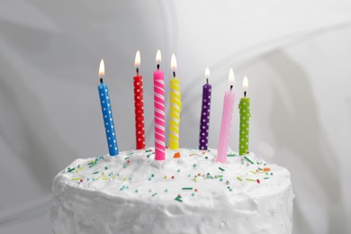 Delicious cake with cream and burning candles on light background, closeup