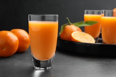 Photo of Delicious tangerine liqueur and fresh fruits on grey table