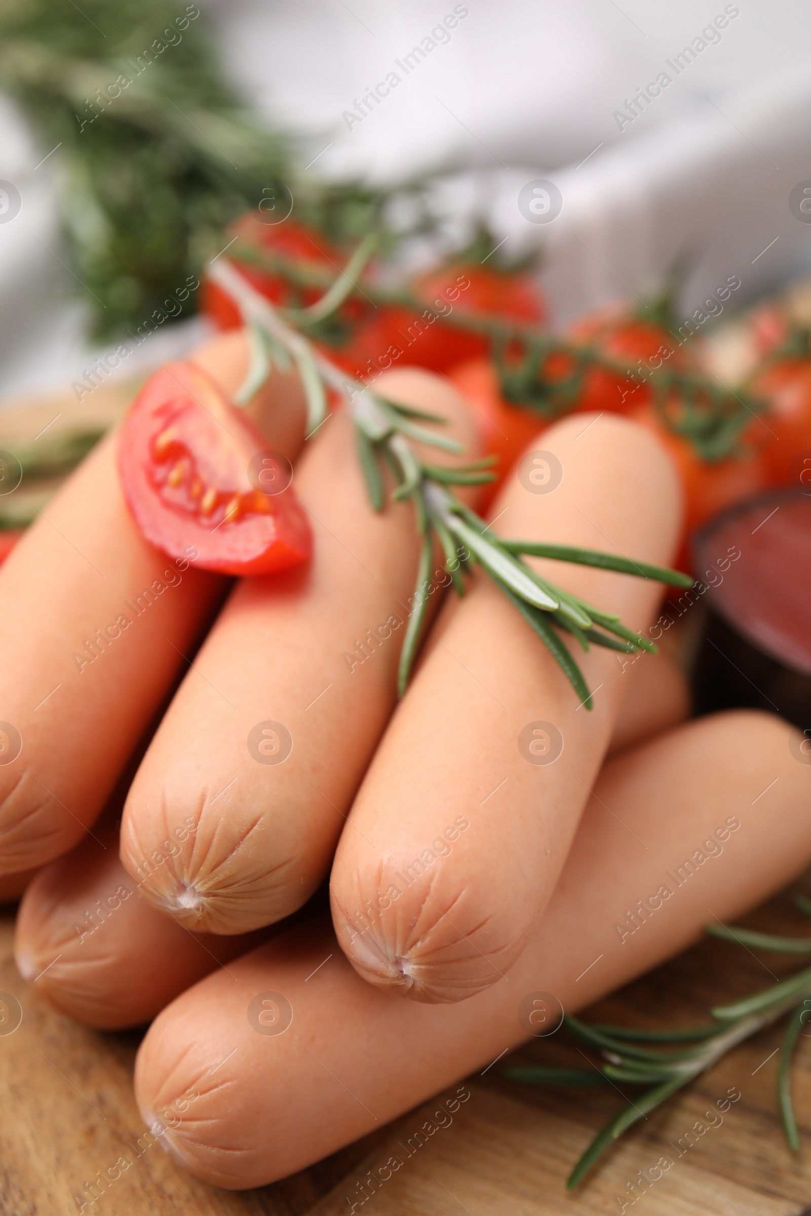 Photo of Delicious boiled sausages, tomato and rosemary on table, closeup