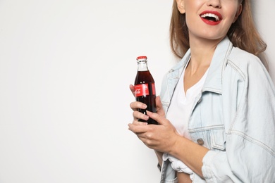 Photo of MYKOLAIV, UKRAINE - NOVEMBER 28, 2018: Young woman with bottle of Coca-Cola on white background, space for text