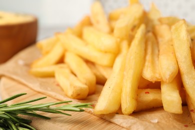 Delicious french fries with rosemary on board, closeup
