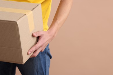 Courier with parcel on beige background, closeup. Space for text