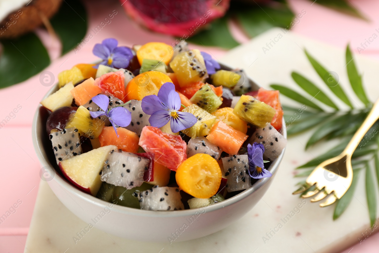 Photo of Delicious exotic fruit salad served on pink table, closeup