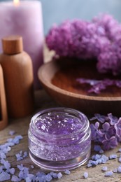 Photo of Cosmetic products and lilac flowers on wooden table, closeup