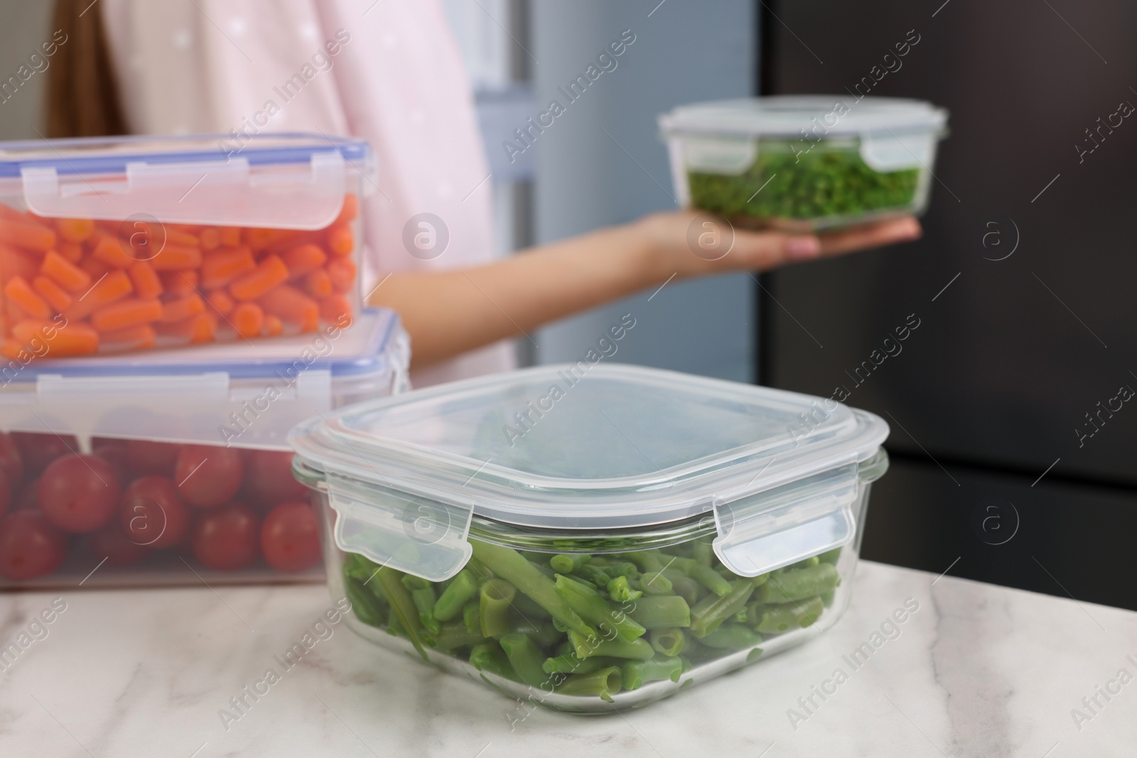 Photo of Glass and plastic containers with different fresh products on white marble table, selective focus