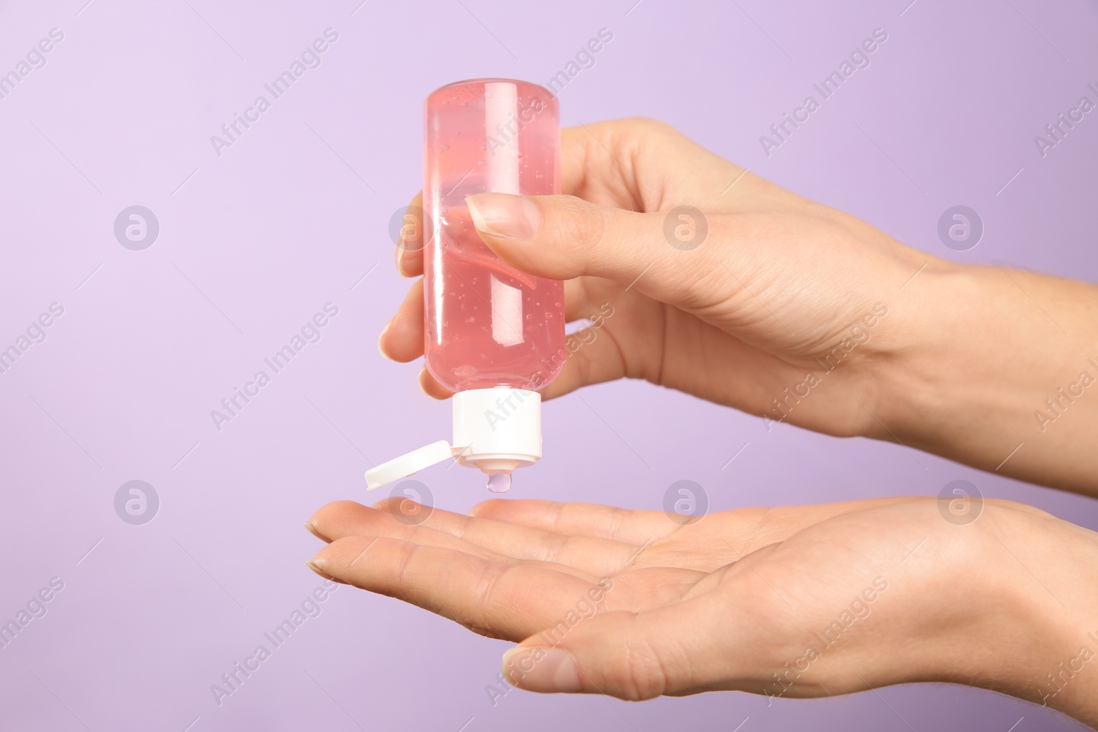 Photo of Woman applying antiseptic gel on lilac background, closeup