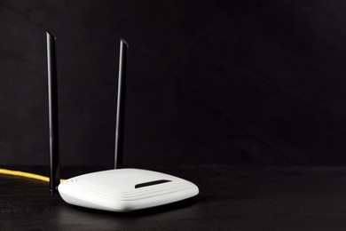 Modern wireless Wi-Fi router on black background. Space for text