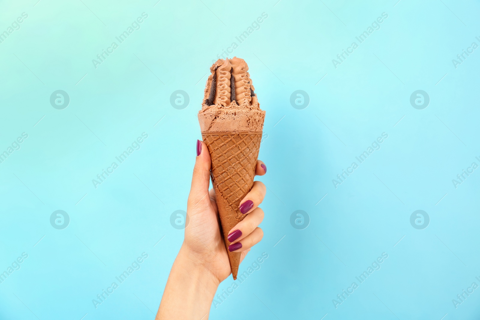 Photo of Woman holding yummy ice cream on color background. Focus on hand