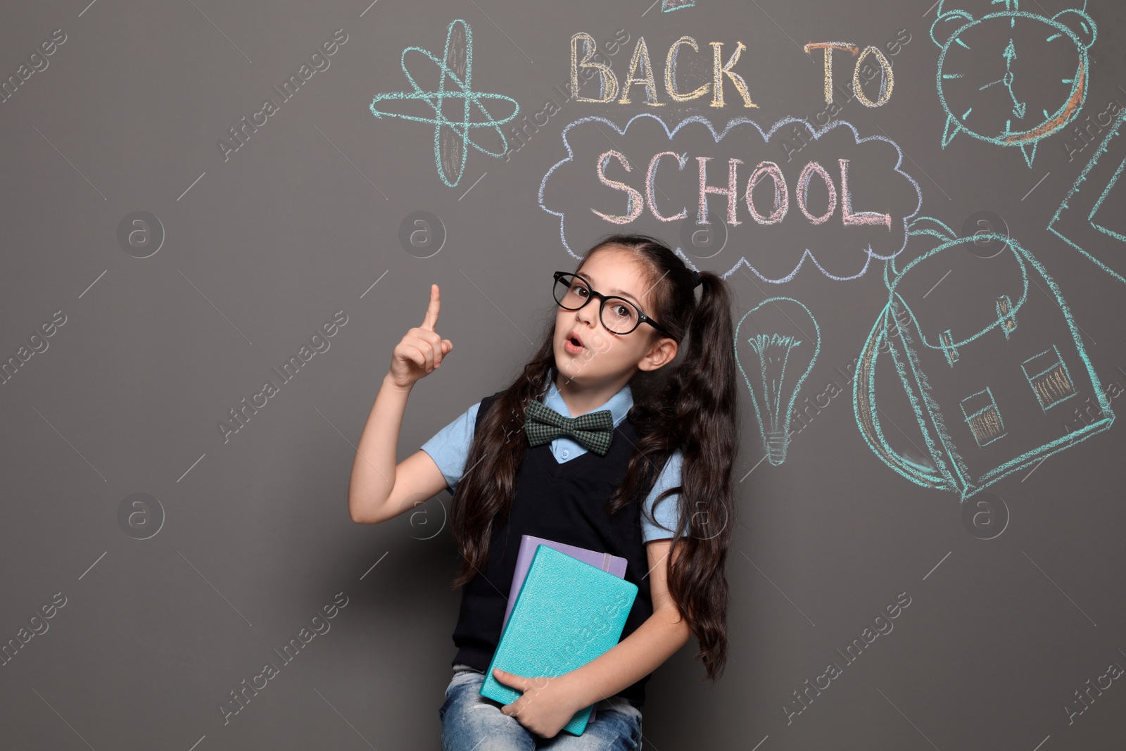 Photo of Little child in uniform near drawings with text BACK TO SCHOOL on grey background