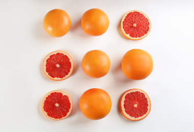 Cut and whole ripe grapefruits on white background, flat lay