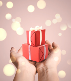 Image of Boxing day. Woman with gifts on beige background, closeup
