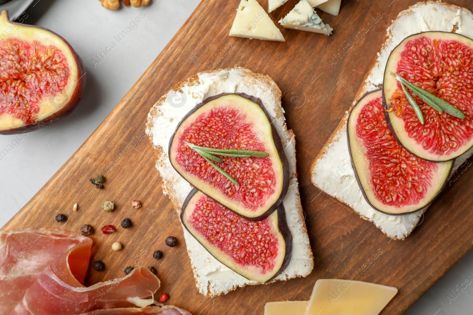 Photo of Sandwiches with ripe figs and cream cheese on wooden board, top view