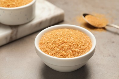 Photo of Brown sugar in bowl on grey table, closeup