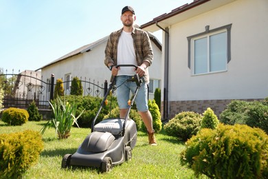 Man cutting green grass with lawn mower in garden