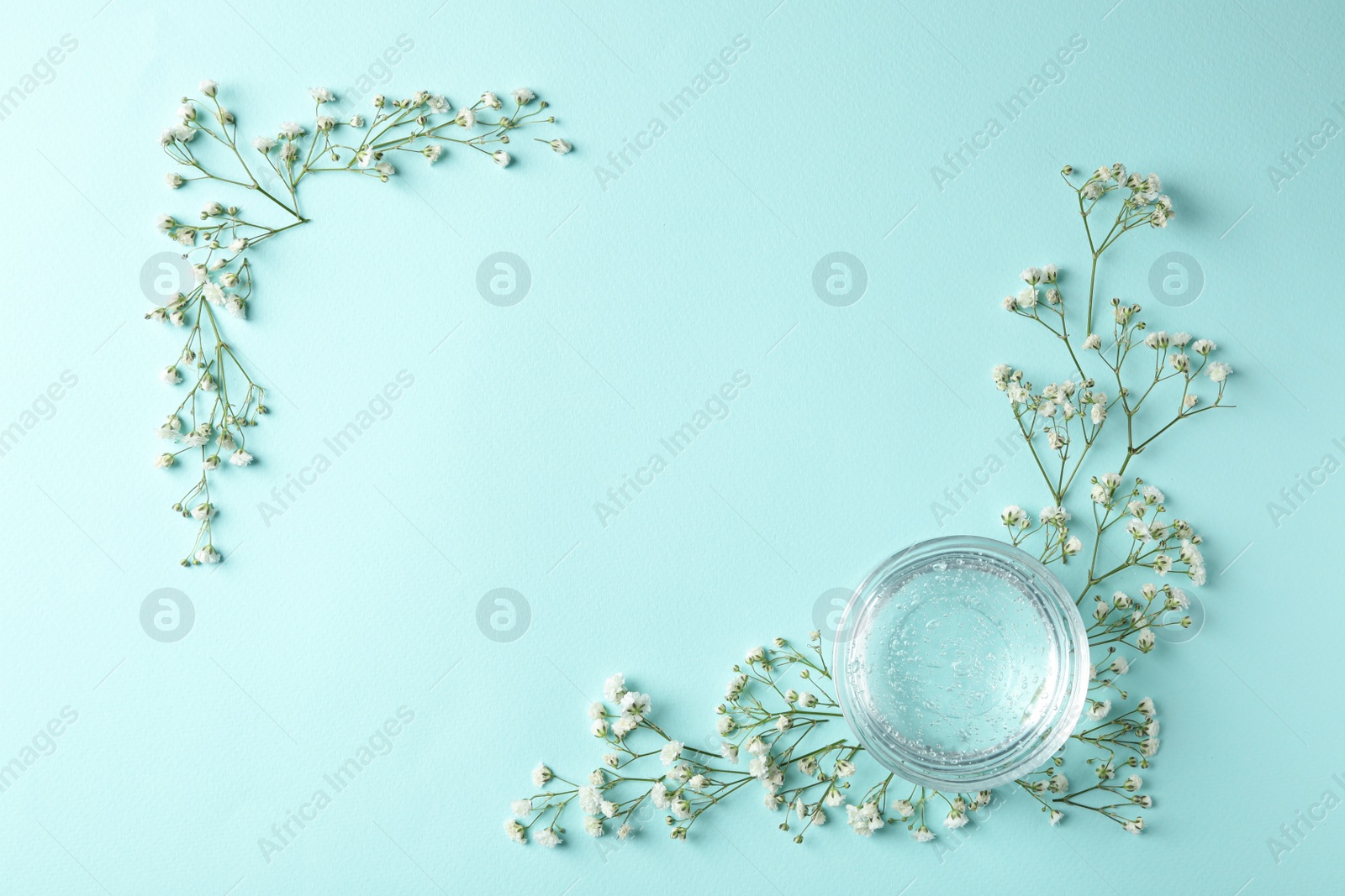 Photo of Flat lay composition with cosmetic gel and beautiful flowers on light blue background. Space for text