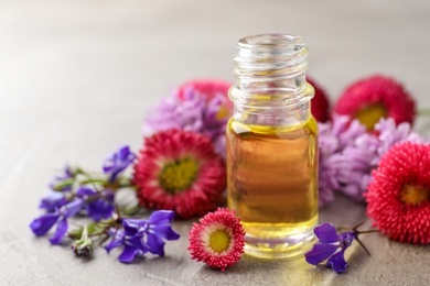 Bottle of essential oil with flowers on table. Space for text