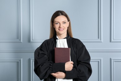 Portrait of smiling judge with book near grey wall