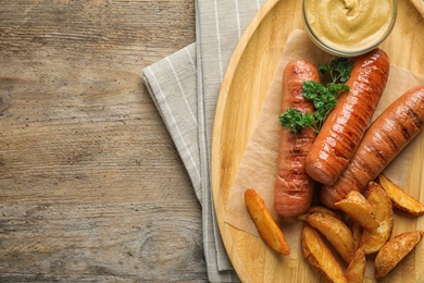 Photo of Flat lay composition with delicious grilled sausages on wooden table, space for text. Barbecue food