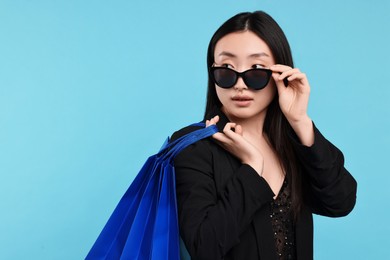 Photo of Beautiful woman with shopping bags on light blue background. Space for text