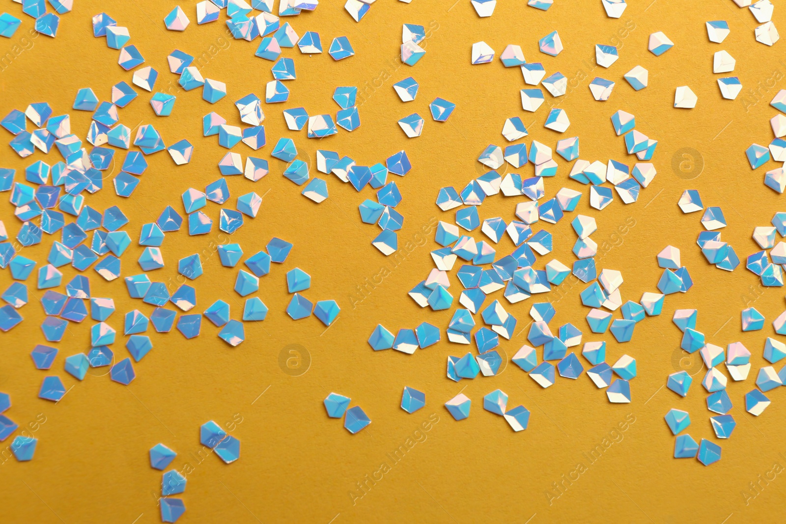 Photo of Shiny bright light blue glitter on yellow background, flat lay