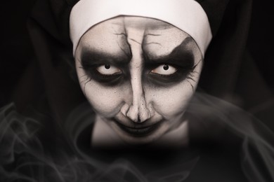 Portrait of scary devilish nun on black background, closeup. Halloween party look