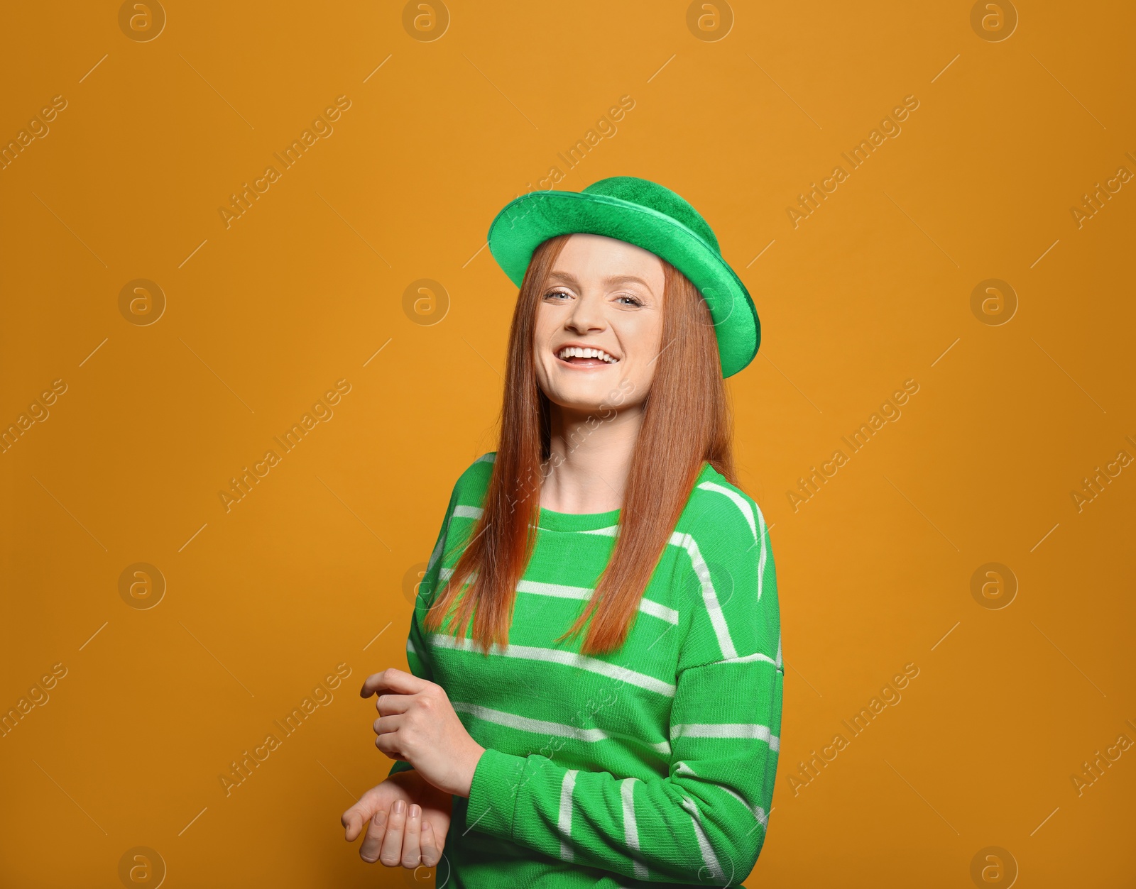 Image of St. Patrick's day party. Pretty woman in green leprechaun hat on golden background