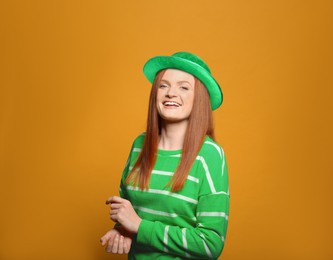 Image of St. Patrick's day party. Pretty woman in green leprechaun hat on golden background