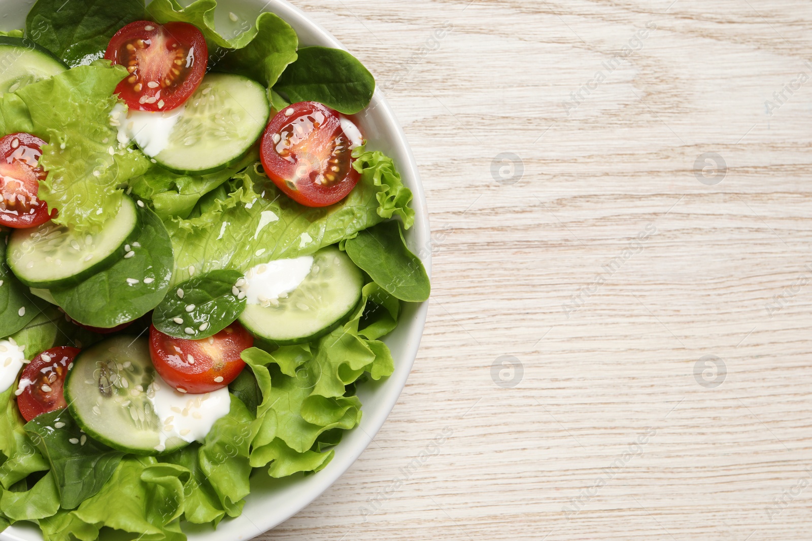 Photo of Delicious salad in bowl on white wooden table, top view. Space for text