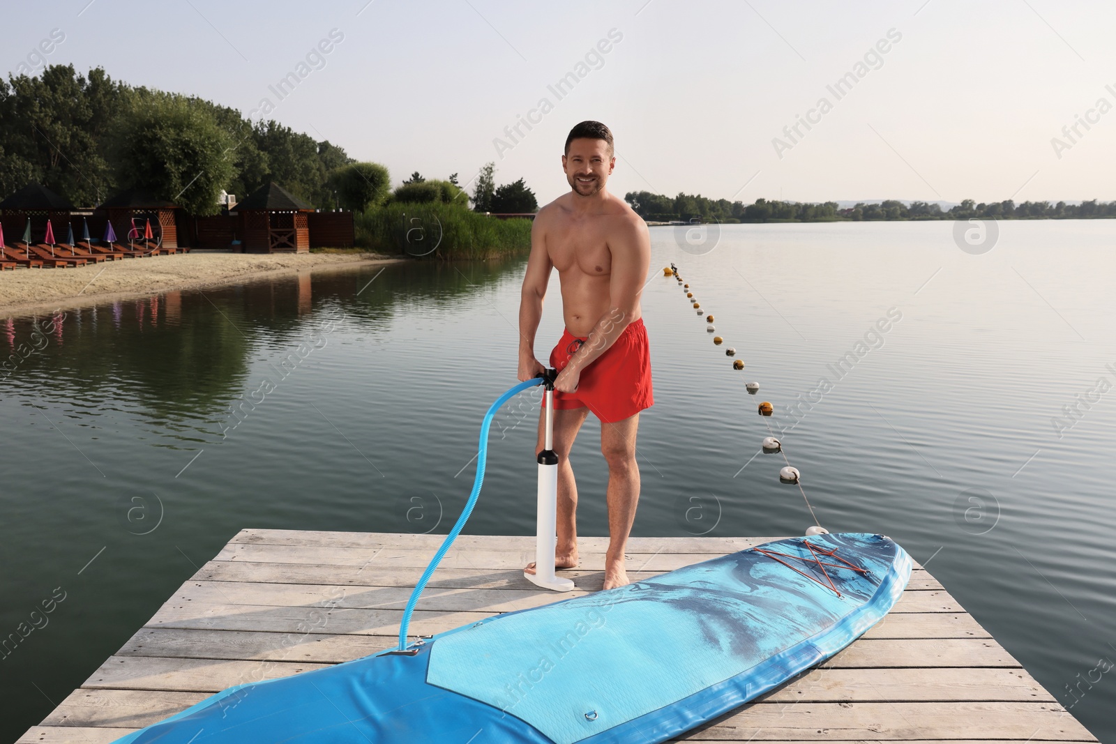 Photo of Man pumping up SUP board on pier
