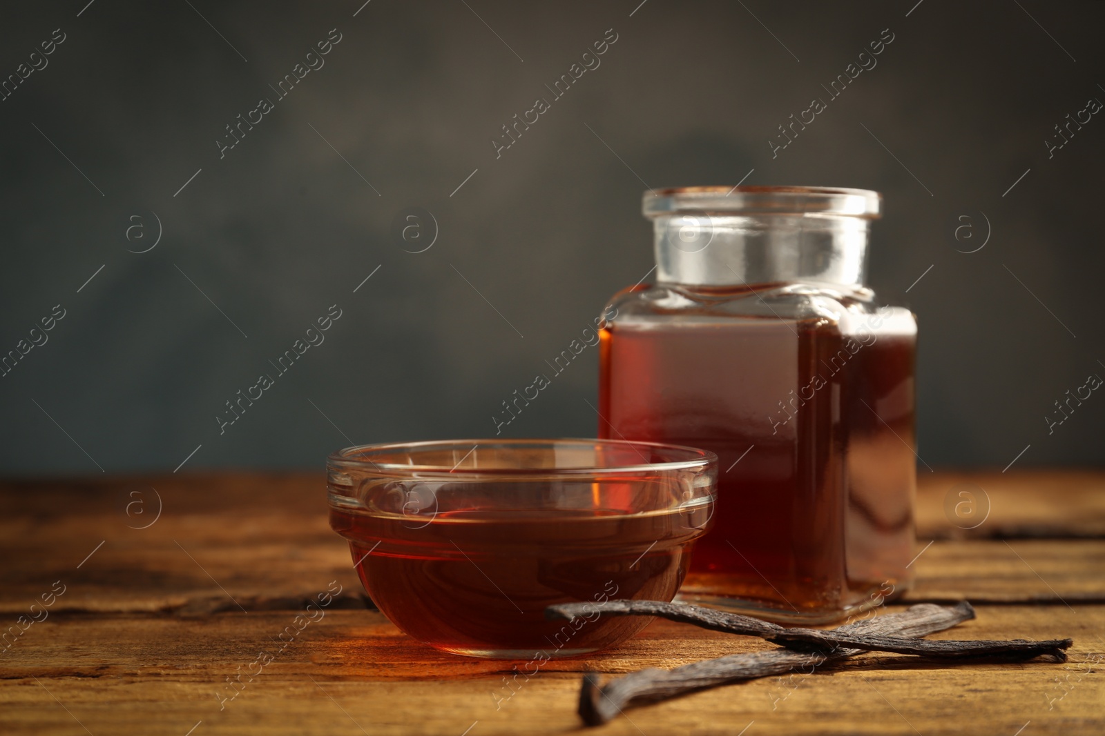 Photo of Aromatic homemade vanilla extract on wooden table