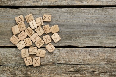 Photo of Runes with different symbols on wooden table, flat lay. Space for text