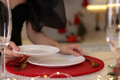 Photo of Woman setting table for Christmas celebration in kitchen, closeup