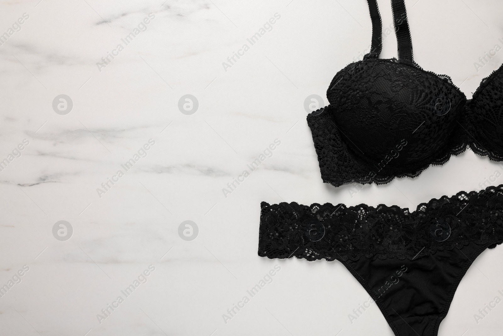 Photo of Elegant black women's underwear on white marble background, flat lay. Space for text