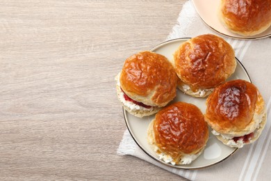 Freshly baked soda water scones with cranberry jam and butter on wooden table, flat lay. Space for text