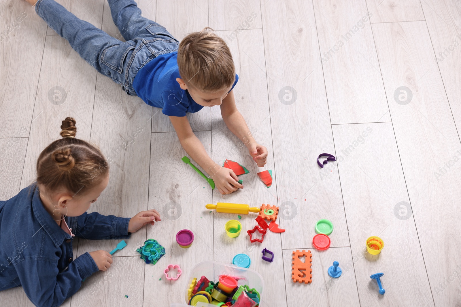 Photo of Cute little children playing on warm floor indoors, space for text. Heating system