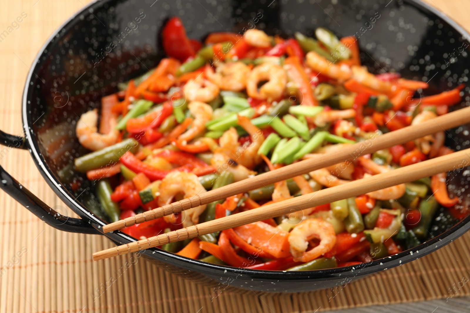 Photo of Shrimp stir fry with vegetables in wok on table, closeup