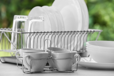 Photo of Set of clean dishes, glasses and cups on table against blurred background