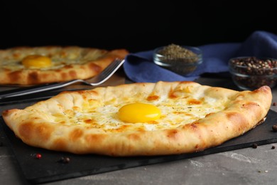 Photo of Fresh homemade khachapuri with cheese and egg on grey table, closeup