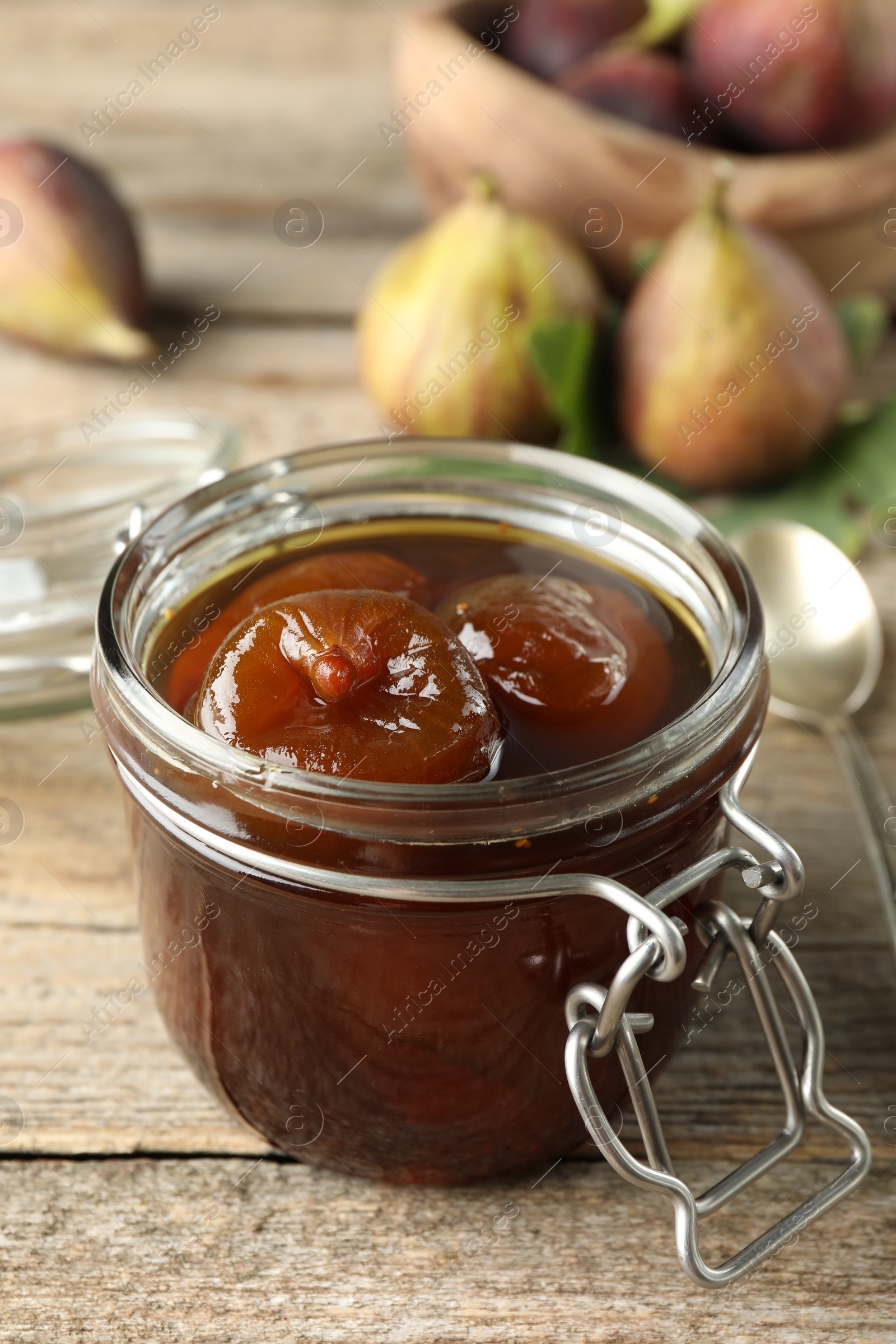 Photo of Jar of tasty sweet fig jam on wooden table