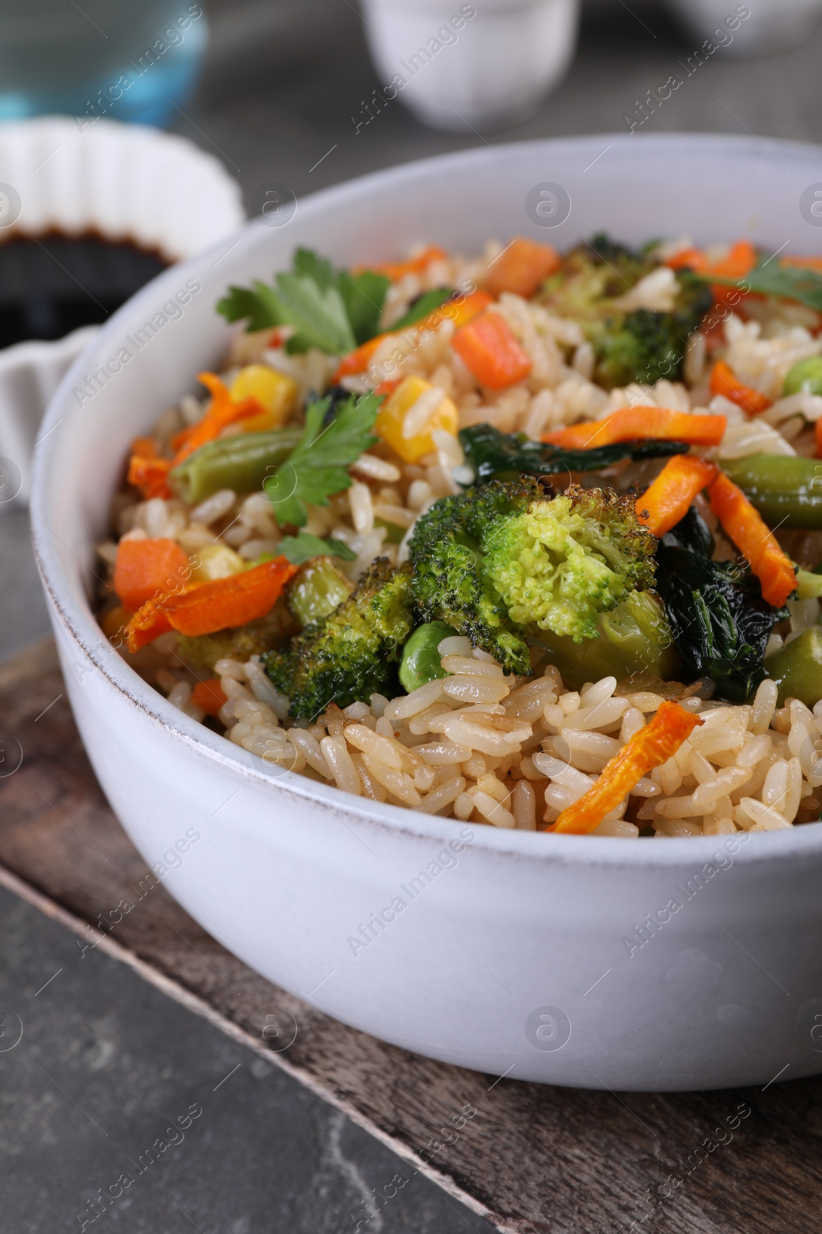 Photo of Tasty fried rice with vegetables on grey table, closeup