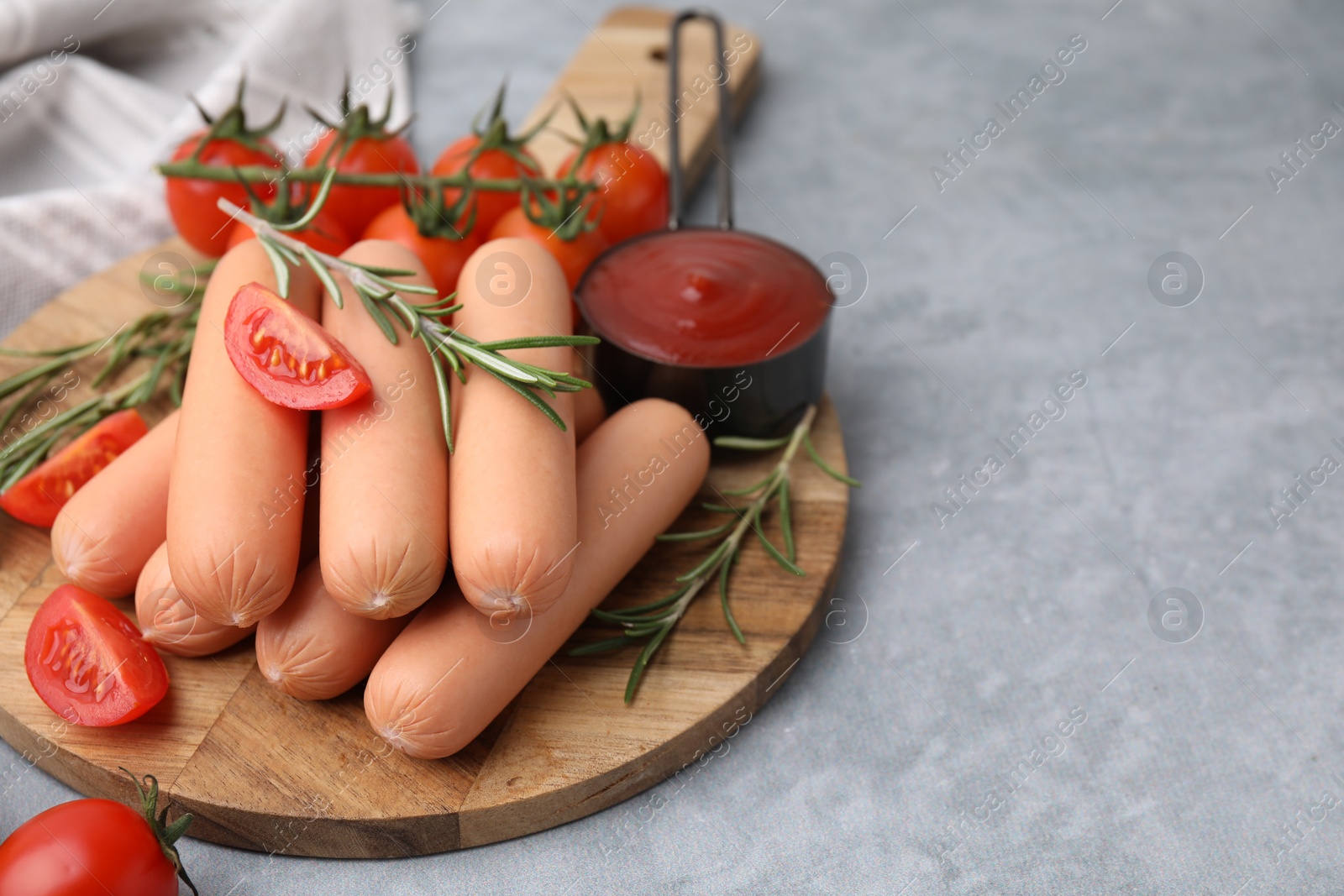 Photo of Delicious boiled sausages, tomato sauce, tomatoes and rosemary on gray table, closeup. Space for text