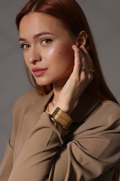 Beautiful young woman with elegant jewelry on gray background