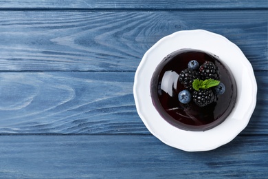 Photo of Delicious fresh jelly with berries on blue wooden table, top view. Space for text