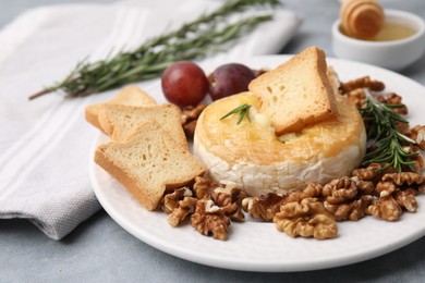 Tasty baked camembert and different products on gray table, closeup