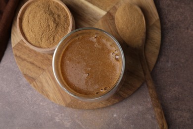 Soluble fiber with water in glass, powder and spoon on brown table, top view