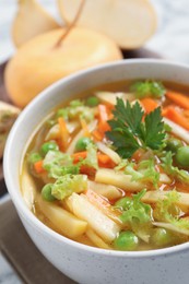 Photo of Bowl of delicious turnip soup on white marble table, closeup