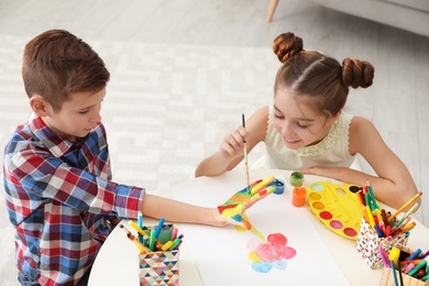 Little children painting hands at table indoors