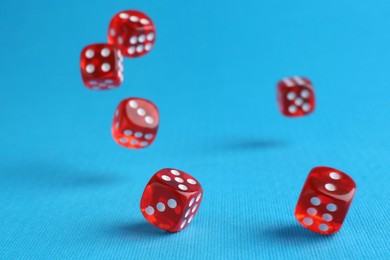 Photo of Many red game dices falling on light blue background